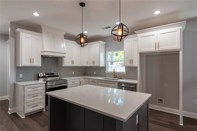 kitchen featuring white cabinetry, hanging light fixtures, custom exhaust hood, and appliances with stainless steel finishes