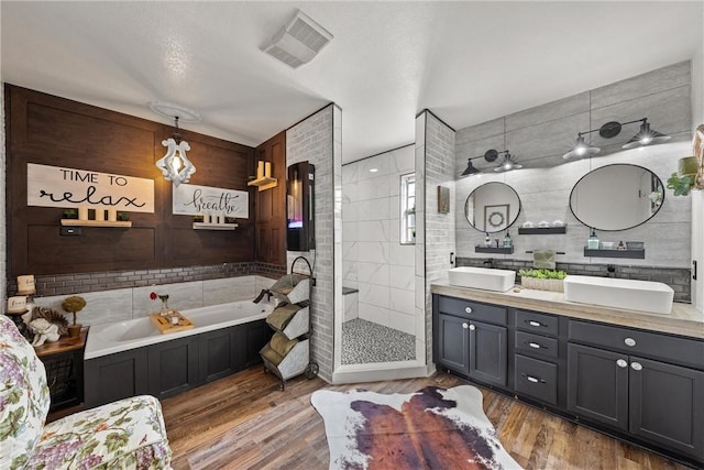 bathroom featuring vanity, hardwood / wood-style floors, plus walk in shower, and tile walls