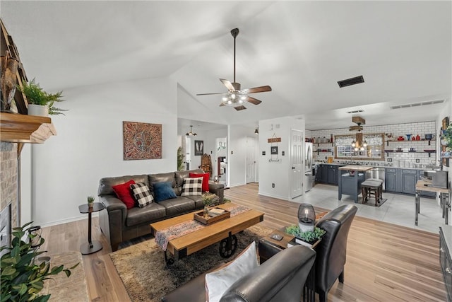 living room featuring a brick fireplace, light hardwood / wood-style floors, and vaulted ceiling