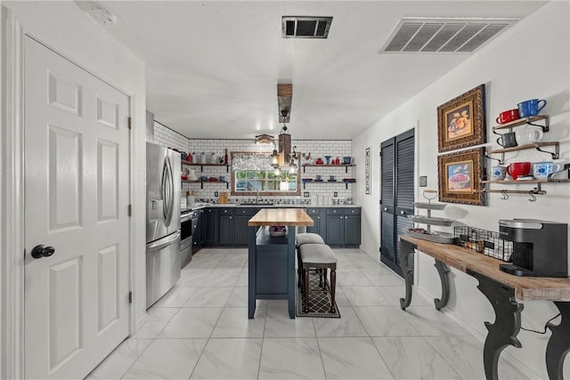 kitchen featuring pendant lighting, wood counters, sink, a kitchen bar, and stainless steel appliances