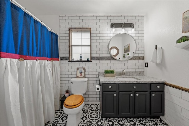 bathroom with tile patterned flooring, vanity, toilet, and tile walls