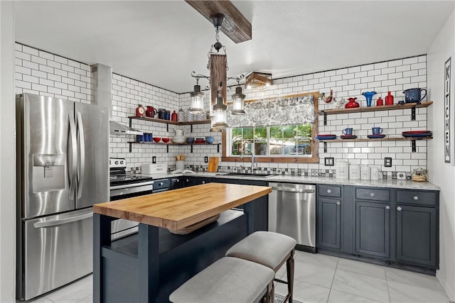 kitchen featuring light stone countertops, a kitchen breakfast bar, backsplash, stainless steel appliances, and sink