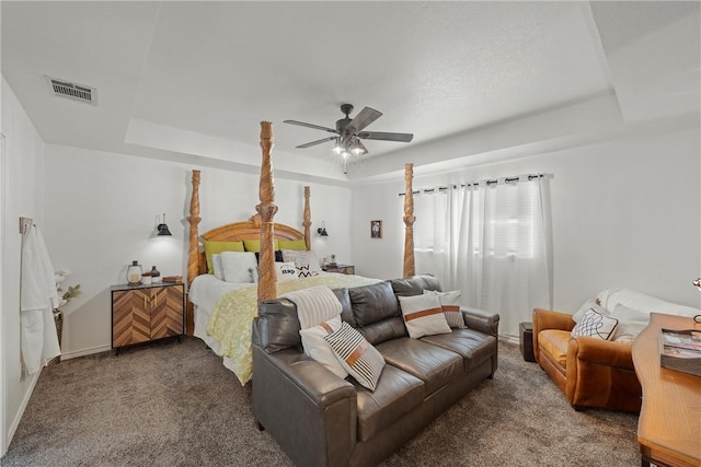 carpeted bedroom with a raised ceiling and ceiling fan