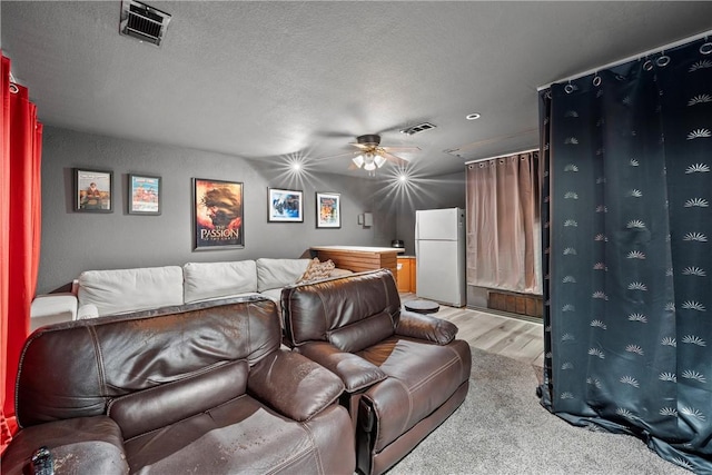 carpeted home theater room featuring ceiling fan and a textured ceiling