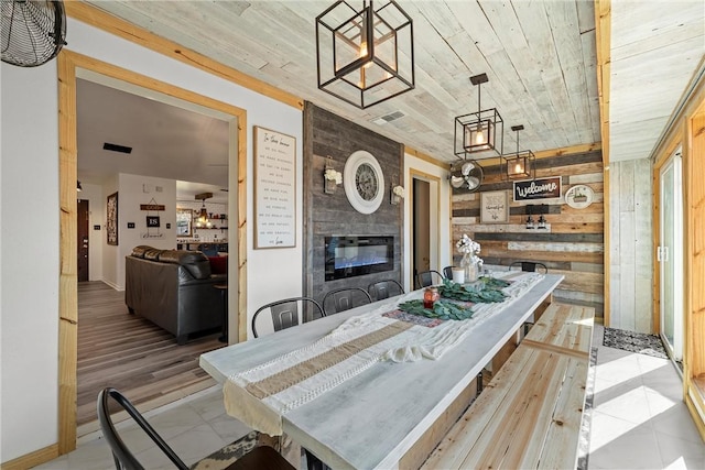 dining space featuring wood walls, wooden ceiling, and a tile fireplace