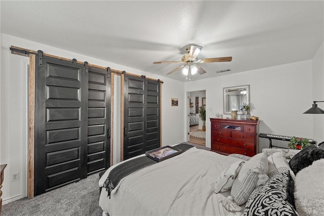 carpeted bedroom featuring ceiling fan and a barn door