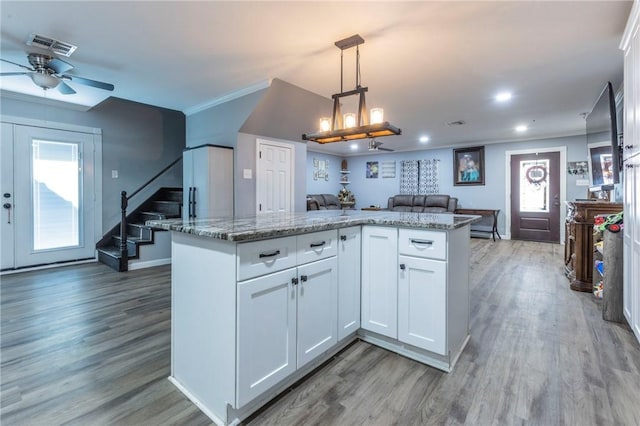 kitchen featuring pendant lighting, wood-type flooring, ceiling fan, light stone countertops, and white cabinetry