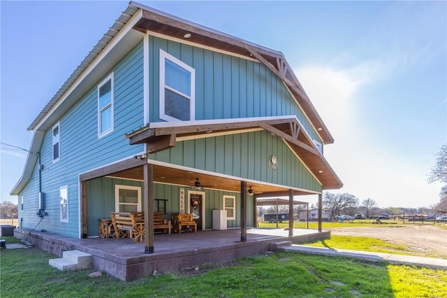 rear view of property with covered porch, central AC unit, and a lawn