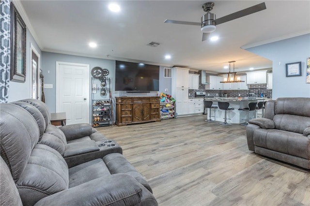 living room featuring ceiling fan, crown molding, and light wood-type flooring