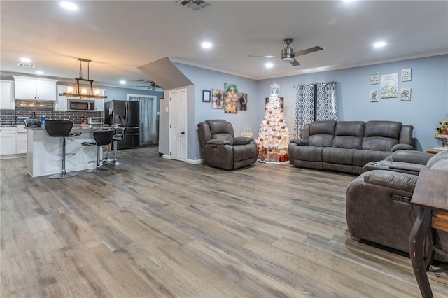 living room featuring ceiling fan, light hardwood / wood-style floors, and ornamental molding