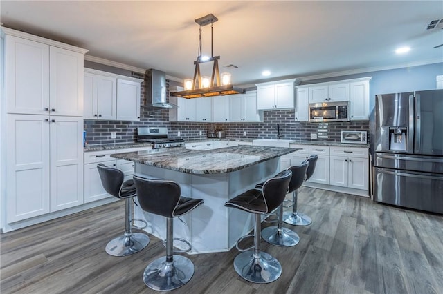 kitchen featuring white cabinets, stone counters, wall chimney range hood, and appliances with stainless steel finishes