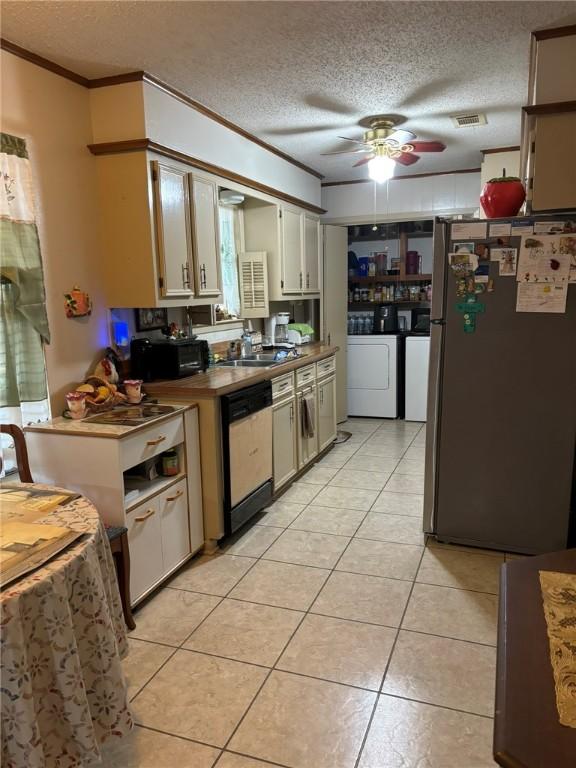 kitchen featuring light tile patterned floors, crown molding, stainless steel appliances, white cabinets, and separate washer and dryer