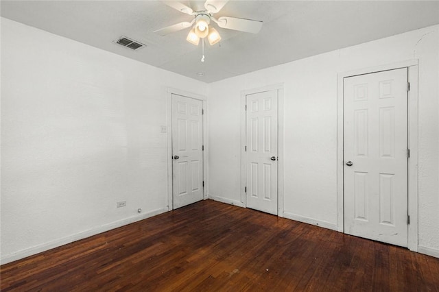 unfurnished bedroom with multiple closets, ceiling fan, and dark hardwood / wood-style floors