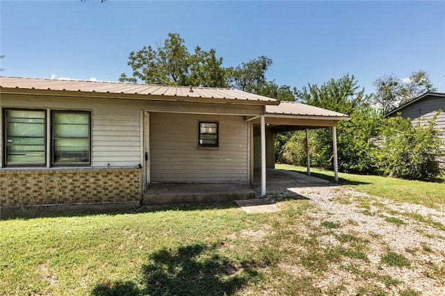 exterior space with a carport and a lawn