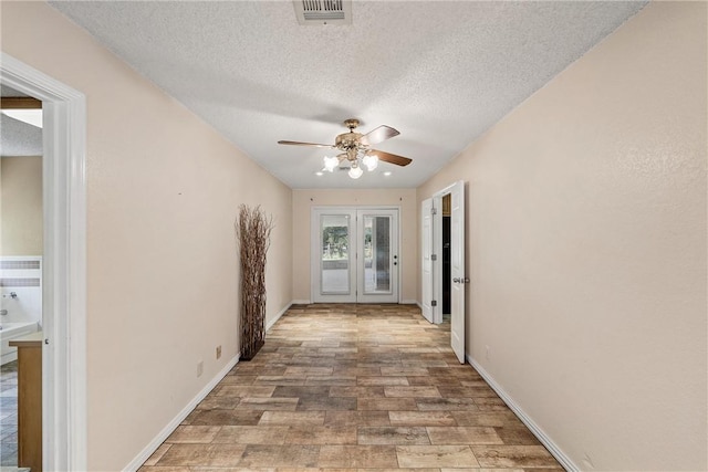 hall featuring french doors, a textured ceiling, and light hardwood / wood-style flooring