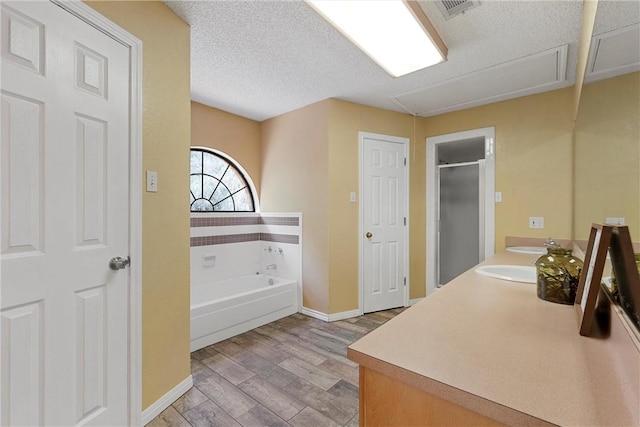 bathroom with vanity, wood-type flooring, a textured ceiling, and plus walk in shower