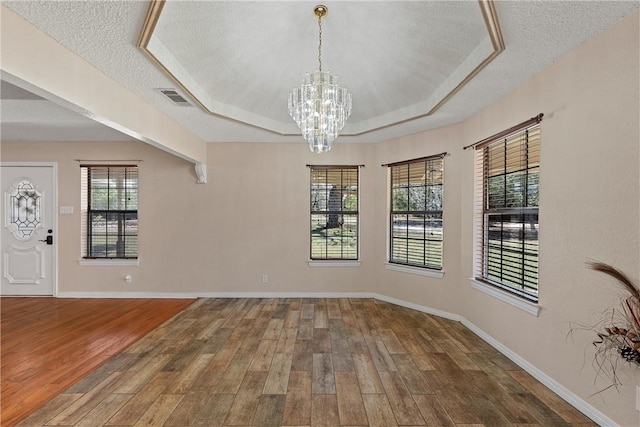 unfurnished dining area with a healthy amount of sunlight, a textured ceiling, and hardwood / wood-style flooring