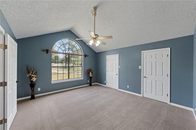 empty room with light carpet, a textured ceiling, ceiling fan, and lofted ceiling