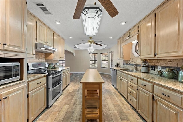 kitchen with light brown cabinetry, sink, light wood-type flooring, and appliances with stainless steel finishes