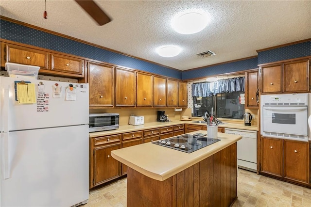 kitchen featuring white appliances, sink, ceiling fan, a textured ceiling, and a kitchen island