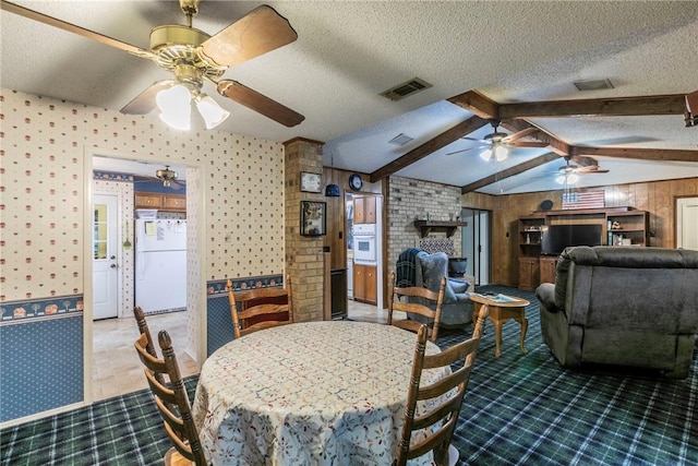 dining room with vaulted ceiling with beams, a textured ceiling, and wood walls