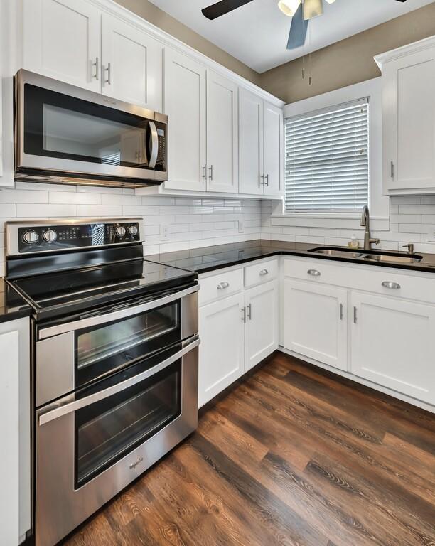 kitchen featuring white cabinetry, sink, stainless steel appliances, tasteful backsplash, and dark hardwood / wood-style flooring