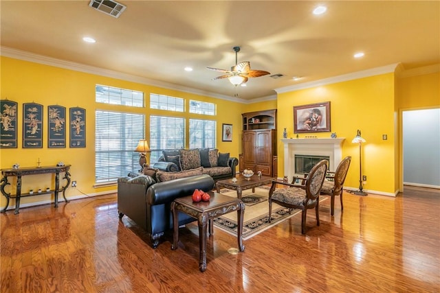 living room featuring hardwood / wood-style floors, ceiling fan, and crown molding