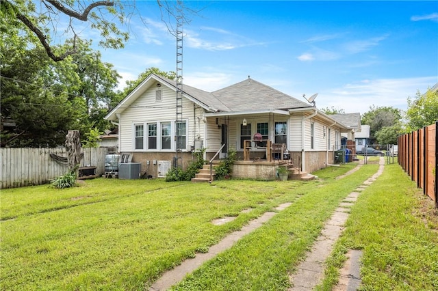 back of house featuring covered porch, central air condition unit, and a lawn