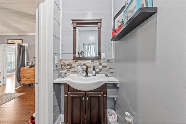 bathroom with backsplash, crown molding, hardwood / wood-style floors, and vanity