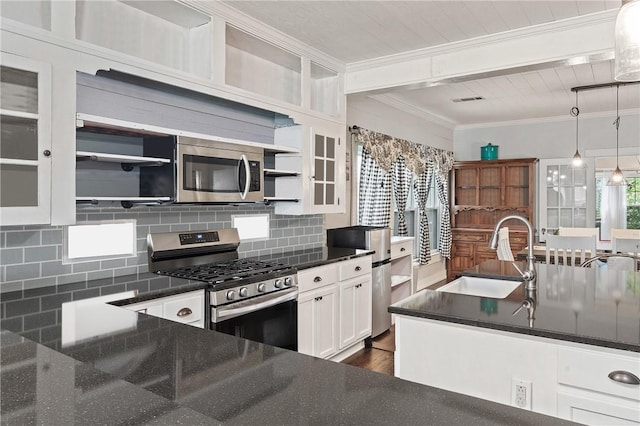 kitchen with appliances with stainless steel finishes, tasteful backsplash, sink, white cabinets, and hanging light fixtures