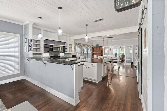 kitchen featuring kitchen peninsula, appliances with stainless steel finishes, a breakfast bar, pendant lighting, and white cabinetry