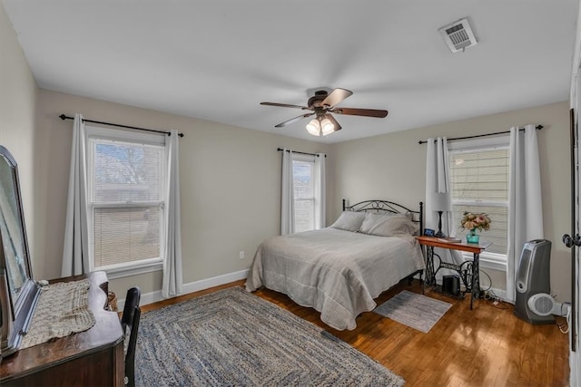 bedroom with visible vents, ceiling fan, baseboards, and wood finished floors