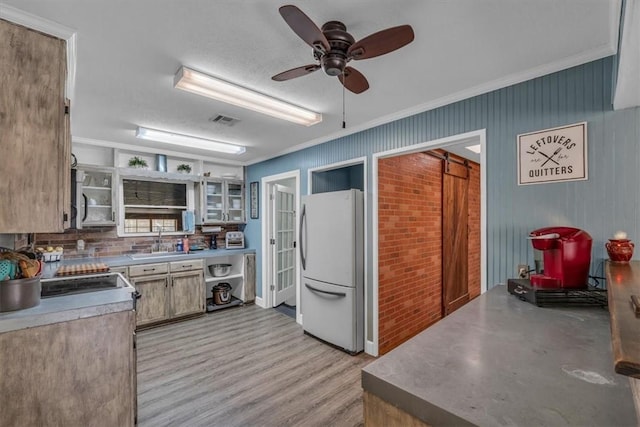 kitchen with visible vents, open shelves, freestanding refrigerator, a sink, and crown molding