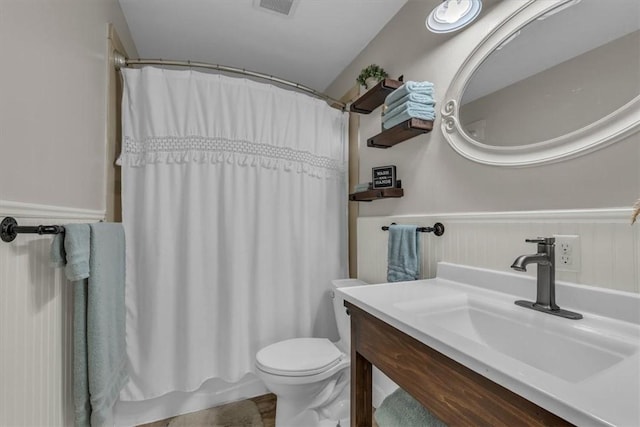 full bath with vanity, toilet, visible vents, and a wainscoted wall