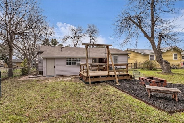 rear view of property featuring a vegetable garden, a deck, a lawn, and a fenced backyard