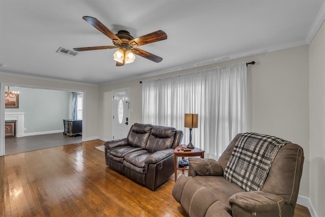 living area featuring crown molding, plenty of natural light, wood finished floors, and baseboards