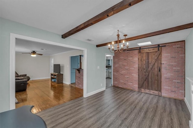 unfurnished living room with visible vents, a barn door, beam ceiling, ceiling fan with notable chandelier, and wood finished floors