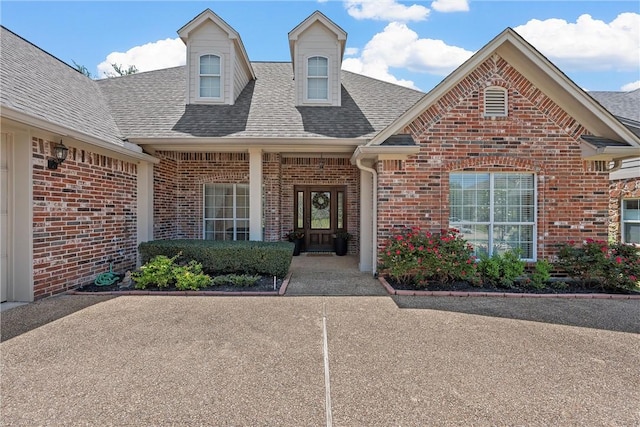 property entrance featuring brick siding and a shingled roof