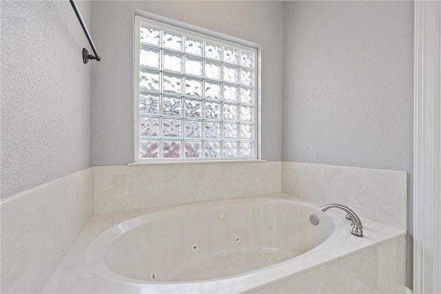 full bath with a whirlpool tub and a textured wall