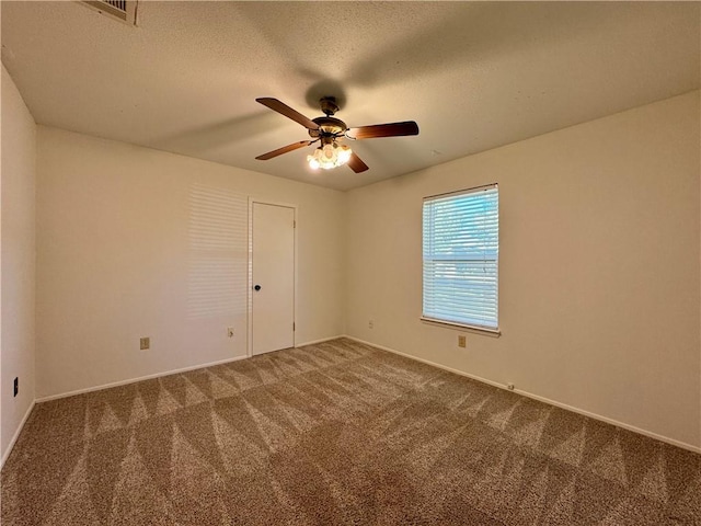 carpeted spare room featuring ceiling fan and a textured ceiling