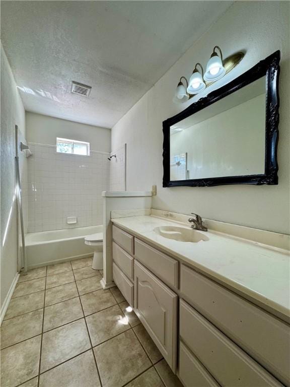 full bathroom with vanity, tiled shower / bath combo, a textured ceiling, tile patterned flooring, and toilet