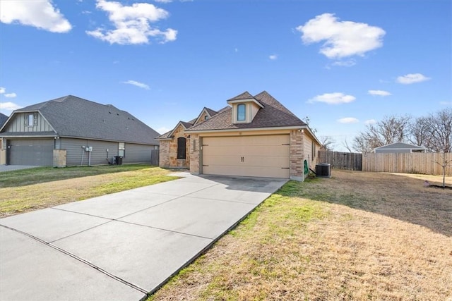 view of front facade featuring a garage, concrete driveway, fence, central AC, and a front yard