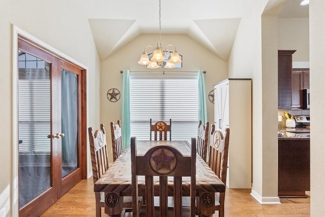 dining space with lofted ceiling, light wood finished floors, and a notable chandelier