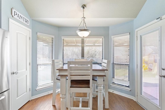 dining area with a wealth of natural light, lofted ceiling, baseboards, and wood finished floors