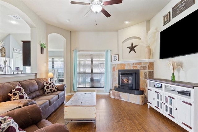 living room with ceiling fan, a stone fireplace, hardwood / wood-style floors, and visible vents