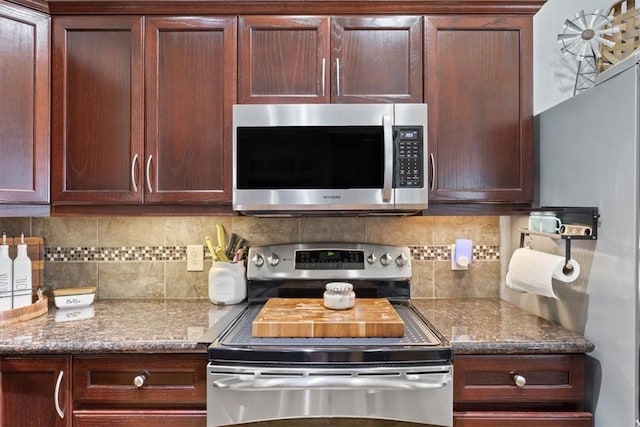 kitchen with stainless steel appliances, dark stone countertops, and backsplash