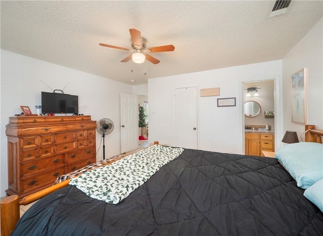 bedroom featuring ensuite bath, ceiling fan, and a textured ceiling