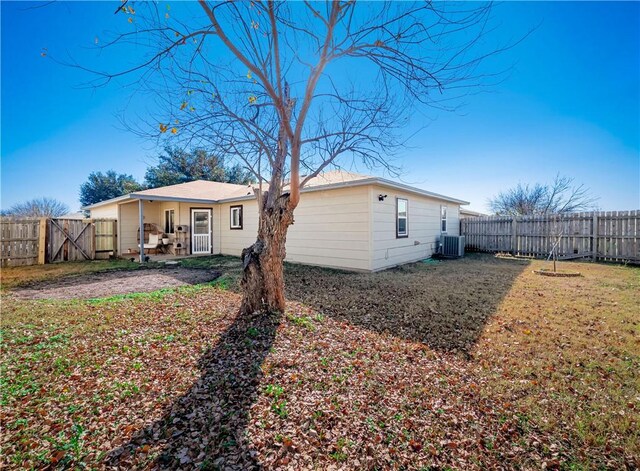 rear view of house featuring a lawn and cooling unit