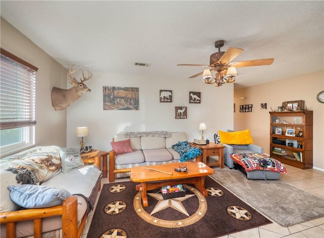 living room with a textured ceiling, ceiling fan, and light tile patterned flooring