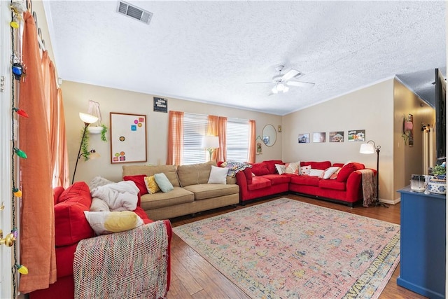 living area featuring dark wood-style flooring, lofted ceiling, visible vents, a ceiling fan, and a textured ceiling